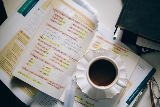 Håndskrevne spanske notater med markeringer og en kopp kaffe
